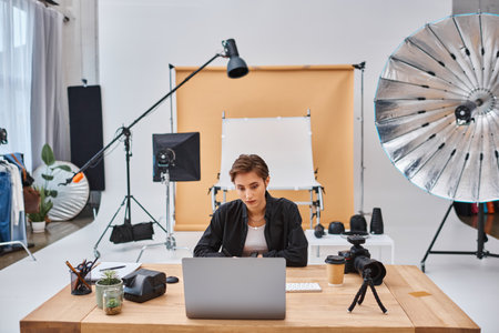 young beautiful female photographer in casual attire working at her laptop with coffee cup on table