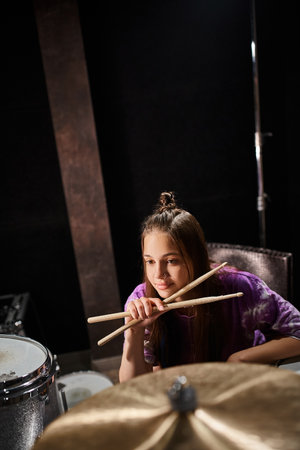 adorable pretty talented teenage girl in vivid attire posing next to drums and looking awayの写真素材