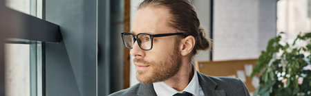 headshot of pensive businessman in grey suit and eyeglasses looking away in modern office, banner