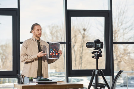 entrepreneur showing document with infographics during video blog on digital camera in office