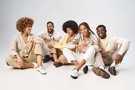group of happy african american friends in casual attire sitting on grey background, Juneteenth