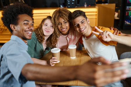excited african american student taking selfie with happy multicultural friends in hostel cafeの写真素材