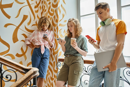 young multicultural friends using smartphones with painted walls in modern students hostel
