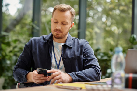 attractive concentrated man in casual outfit working on his startup with his laptop in office
