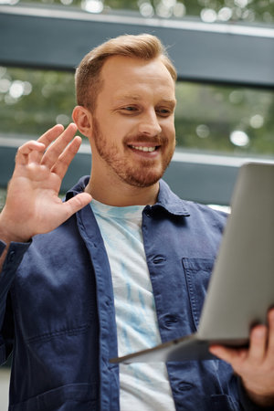 cheerful good looking architect in everyday clothes holding his laptop and working on his startupの写真素材