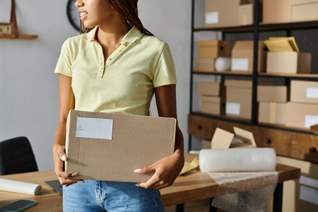 cropped view of young african american female retailer holding cardboard box, delivery conceptの写真素材