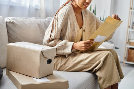 cropped view with focus on cardboard boxes next to blurred african american woman with post packetの写真素材