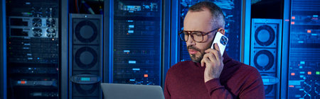 devoted specialist in turtleneck talking by phone and looking at his laptop, data center, banner