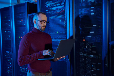 good looking concentrated specialist in turtleneck with beard working on his laptop attentively