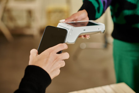 smartphone payment, cropped view of man holding his smartphone near card reader in vegan cafe