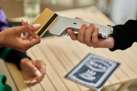 female customer holding credit card near card reader, cropped hand on woman paying in vegan cafeの写真素材