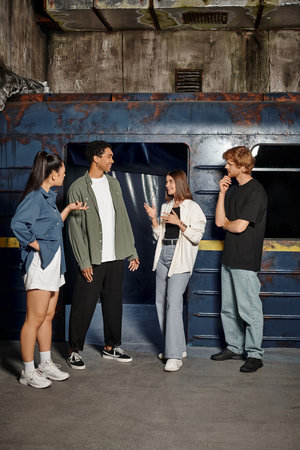 group of four happy multicultural friends deciding on strategy in an underground quest room