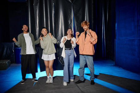group of four interracial friends celebrating success in an escape room challenge, rejoice