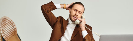 good looking man with beard in elegant suit talking by retro phone with legs on table, banner
