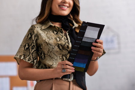 cropped view of smiling and stylish designer holding color samples in private clothes atelierの写真素材