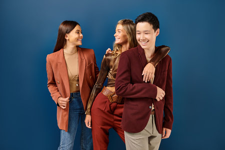 jolly brunette and blonde teenage girls smiling at each other next to their stylish asian friend