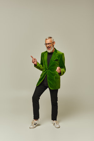 joyful handsome mature male model in stylish outfit with beard and glasses smiling at cameraの写真素材
