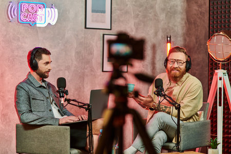 cheerful men in comfortable attires with coffee and laptop during their discussion on podcast