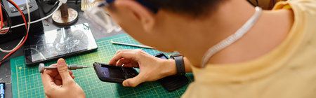 back view of technician with screwdriver assembling mobile phone in repair shop, horizontal banner