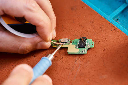 partial view of technician soldering electronic microscheme in repair shop, maintenance service