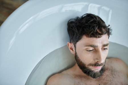 depressed frustrated man with beard lying in bathtub during breakdown, mental health awarenessの写真素材