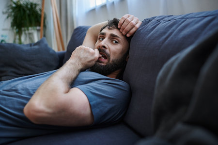 depressed hopeless man in cozy home wear lying on sofa during mental breakdown, psychotherapy
