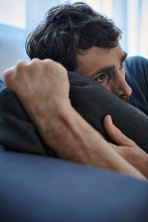 frustrated bearded man in casual home wear lying on sofa during breakdown, mental health awareness