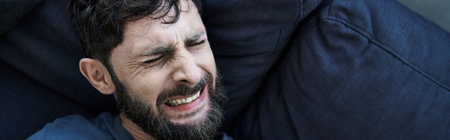 anxious man with beard in casual clothes suffering during breakdown, mental health awareness, banner