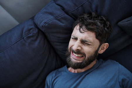 anxious man with beard in casual clothes suffering during breakdown, mental health awarenessの写真素材