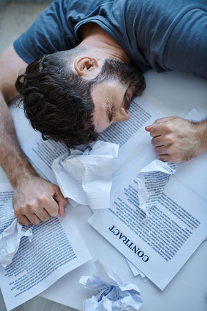 desperate man next to his papers and contract during depressive episode, mental health awareness