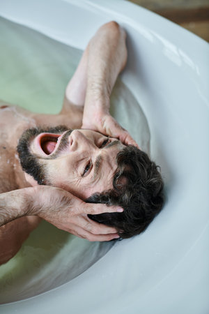 emotional traumatized man lying in bathtub  and screaming during breakdown, mental health awareness
