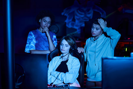 tensed diverse female gamers looking at monitor while thinking on game strategy, cybersport