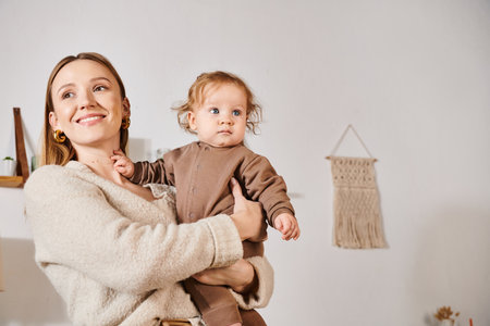 cheerful smiling woman holding and embracing baby boy in cozy nursery room, blissful motherhood