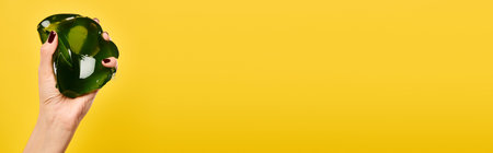 object photo of mouthwatering green jello in hand of unknown woman on yellow backdrop, banner