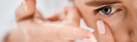 beautiful woman in white comfy bathrobe wearing her contact lenses near mirror in bathroom, bannerの写真素材