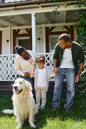 happy moments, jolly african american parents and son smiling near family dog on backyard of houseの写真素材