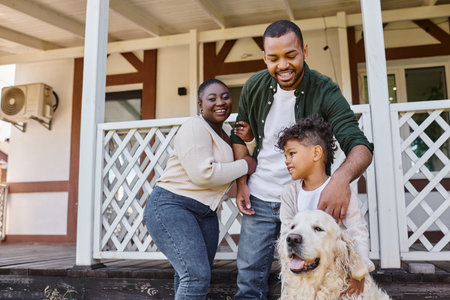 family photo, happy african american parents and son playing with dog on backyard of their houseの写真素材