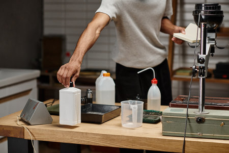 cropped african american photographer taking chemical solution in bottle, film development