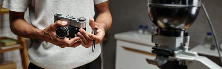 cropped banner of black man Intently holding an analog camera and pen while standing in a photo labの写真素材