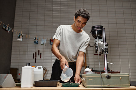 meticulous process of film development, african american man pouring chemical solution in tray