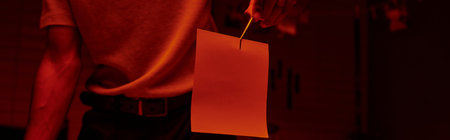 cropped banner of photographer holding tweezers with photo paper in a darkroom with red lightの写真素材