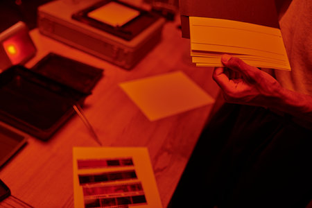 cropped african american photographer counting printed photos while holding envelope in darkroomの写真素材