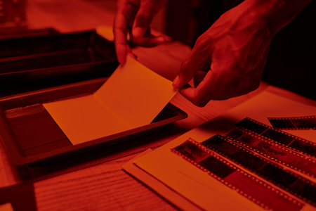 cropped photographer skillfully prepares a film negative for photo development in darkroomの写真素材