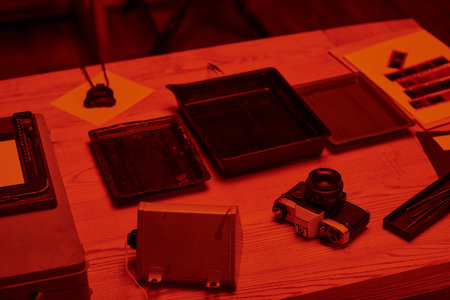 A table with analog camera and tools for film development in darkroom with red light, nostalgiaの写真素材