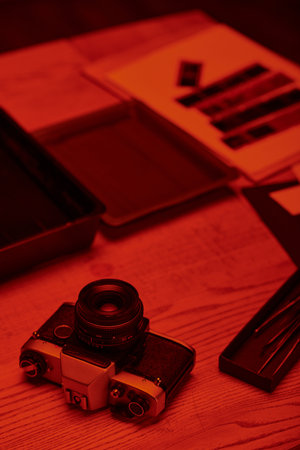 A darkroom table with analog camera and tools for film development under the glow of red lightの写真素材