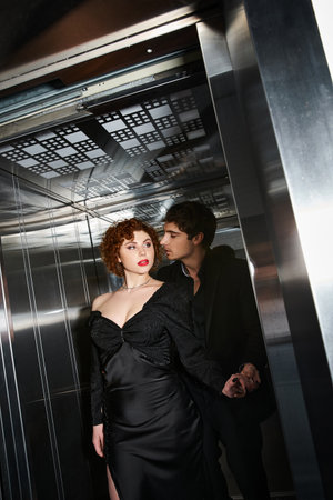 sexy appealing couple in elegant black dress and suit hugging lovingly in elevator after date