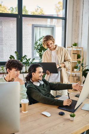 happy post production team focused on a retouching project in office, man with laptop near coworkers
