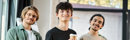 Three happy young professionals in their 20s with coffee in a friendly office atmosphere, banner