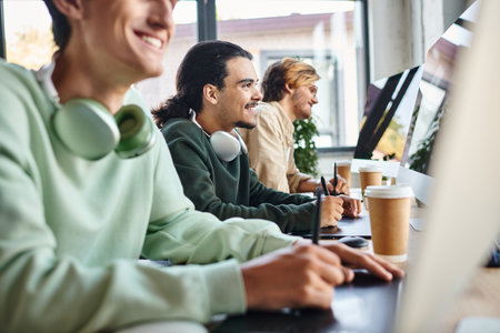 post production team smiling and editing photos in modern office space, cheerful men in 20s