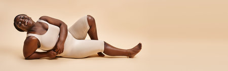 banner of happy plus size african american young woman reclining against beige backdrop